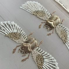 two gold and white lace appliques sitting on top of a table