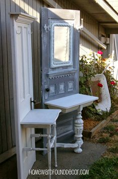 an old door is painted white and sits next to a small table in front of a house