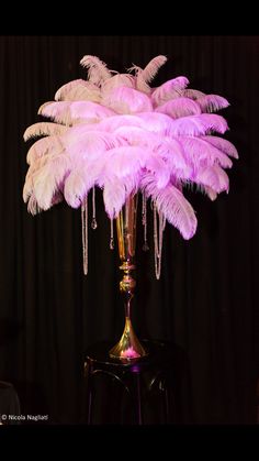 a tall vase filled with lots of pink feathers on top of a black tablecloth