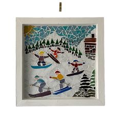 a white frame holding a stained glass mosaic with people skiing and snowboarding in the woods