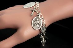 "A Pieta medal combined with a collection of silver plated Christian theme charms have been dispersed around a shimmering silver plated bracelet chain in this handmade charm bracelet. This religious charm bracelet is then completed with a lobster clasp and a 1/2 inch of chain at the end for adjustable sizing. ● Bracelet Styles ● Style #1 - Charms in this bracelet include a \"Christ Carrying the Cross\" charm, praying hands charm, a \"So Very Blessed\" charm, a Jesus fish charm, a \"Jesus loves y Nickel Free Silver Metal Rosary Bracelet, Nickel-free Silver Metal Rosary Bracelet, Personalized Spiritual Silver Charm Bracelet, Spiritual Silver Rosary Bracelet With Charms, Adjustable Silver Rosary Bracelet With Charms, Silver Nickel-free Spiritual Charm Bracelet, Symbolic Silver Rosary Bracelet For Gifts, Vintage Silver Rosary Bracelet As Gift, Symbolic Silver Rosary Bracelet Gift