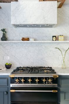 a stove top oven sitting inside of a kitchen next to a shelf filled with pots and pans