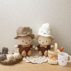 two stuffed animals sitting next to each other on top of a wooden table in front of a white wall