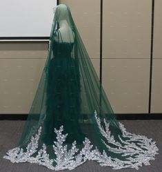 a green wedding dress with white lace on the bottom and veil hanging down from it