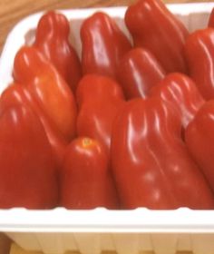 a white container filled with red peppers on top of a wooden table