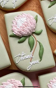 decorated cookies with pink flowers and thank you written on the top are arranged in rows