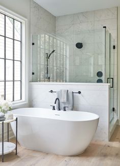 a large white bathtub sitting in the middle of a bathroom next to a walk in shower