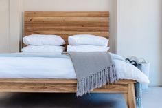 a wooden bed with white sheets and pillows