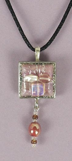 This pretty dimensional ENCASED JEWEL NECKLACE was handcrafted by Sandi Obertin.  It features a one (1) inch metal square that is embellished with pearl and glass components and a beaded dangle element.   The overall length of the pendant including the bale is approximately 2-1/2 inches .  It comes with a black satin cord and is ready to wear.  It would add the finishing touch a variety of clothing necklines and colors. Handmade Metal Square Pendant Jewelry, Rectangular Pearl Pendant Necklace As A Gift, Rectangular Pearl Pendant Necklace For Gift, Handmade Square Jewelry As Gift, Handmade Square Jewelry Gift, Unique Nickel-free Rectangular Jewelry, Unique Nickel Free Rectangular Jewelry, Nickel-free Square Silver Jewelry, Nickel-free Adjustable Square Pendant Jewelry