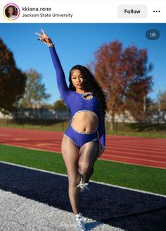 a woman in a blue bodysuit is standing on a track with her arms up