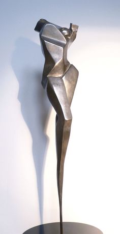 a metal sculpture sitting on top of a wooden table next to a white wall and floor