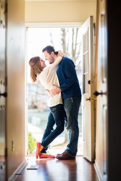 a man and woman standing in an open door with their heads close to each other