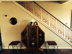 a living room with a clock on the wall and two stools in front of it