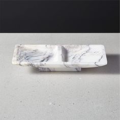 a white marble soap dish on a gray surface