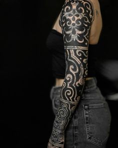 a woman with black and white tattoos on her arm is standing in front of a black background