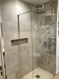 a walk in shower sitting inside of a bathroom next to a tiled wall and floor