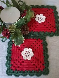 two crocheted placemats sitting on top of a table next to a candle