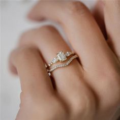 a woman's hand with two diamond rings on her left and the other hand holding an engagement ring