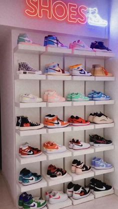 there are many shoes on the shelves in this store that is lit up with neon lights