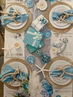 the table is set with blue and white plates, napkins, seashells and starfish