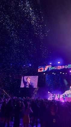 the stage is lit up with purple lights and confetti falling from the sky