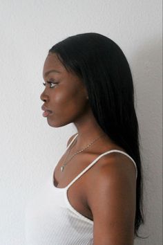 a woman standing in front of a white wall with her hand on her hip and looking off to the side