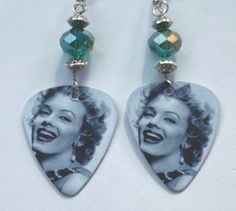 a pair of earrings with an image of marilyn monroe on it and beads hanging from them