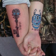 two people holding hands with tattoos on their arms and the other hand has a blue skull