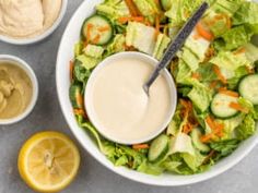 a bowl filled with salad and dressing next to sliced lemons