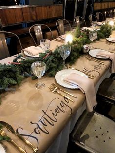 a long table with place settings and greenery on it is set for an elegant christmas dinner