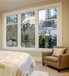 a bedroom with a bed, chair and large windows