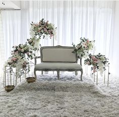 a white couch sitting on top of a shaggy rug next to flowers and vases