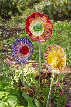 three colorful glass flowers in a garden