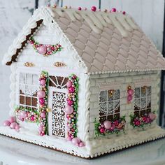 a white gingerbread house decorated with pink and green decorations