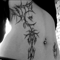 a woman's stomach with tattoos on it and an image of a plant growing out of the side