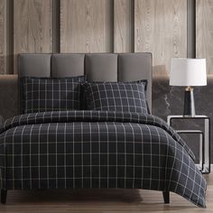 a black and white plaid comforter set on a bed with two lamps next to it