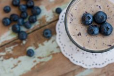 three blueberries sit on top of a smoothie in a glass with some milk