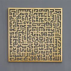 an intricately designed gold metal piece on the side of a gray wall with black and white designs