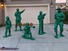 a group of statues of soldiers in front of a house with pumpkins on the ground