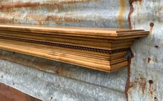 a close up of a wooden shelf on a wall with rusted metal behind it