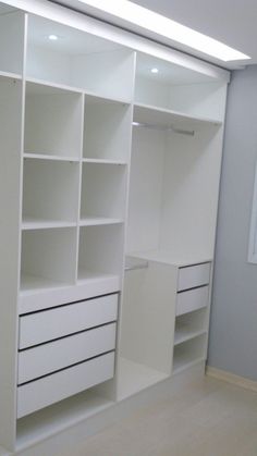 an empty closet with white shelves and drawers