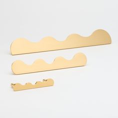 two pieces of brass metal on a white surface with one piece cut out to look like waves