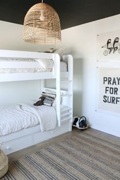 a white bunk bed sitting next to a wall with pictures on it and a basket hanging from the ceiling