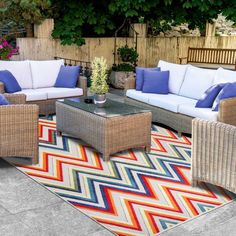 a patio with wicker furniture and colorful rug