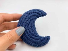 a crocheted crescent is being held by someone's hand with their thumb