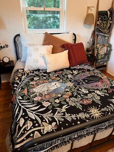 a bed with many pillows on top of it in a bedroom next to a window