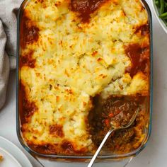 a casserole dish with meat and cheese in it on a white tablecloth