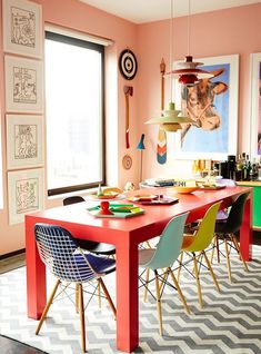 a dining room with pink walls and colorful chairs