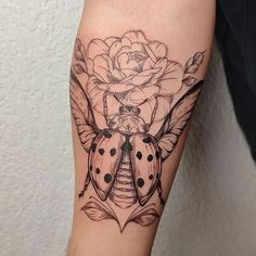 a ladybug and rose tattoo on the arm