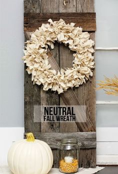 a wooden door with a wreath hanging on it's side and the words neutral fall wreath below